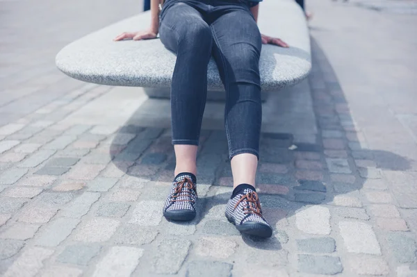 Jeune femme assise sur banc de granit — Photo