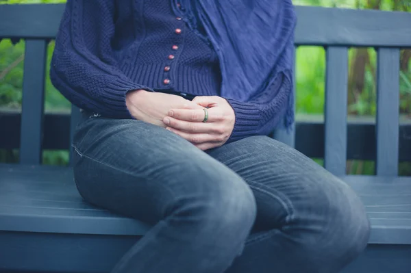 Ung kvinna sitter på bänken utanför — Stockfoto