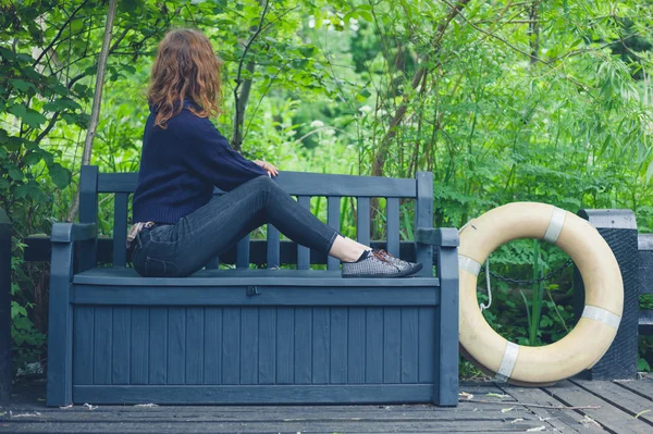 Fiatal nő pihentető padon a természetben — Stock Fotó