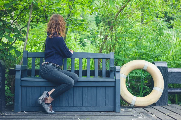 Mladá žena uvolňující na lavičce v přírodě — Stock fotografie
