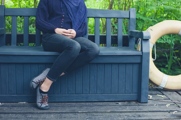 Jeune femme assise sur un banc à l'extérieur — Photo