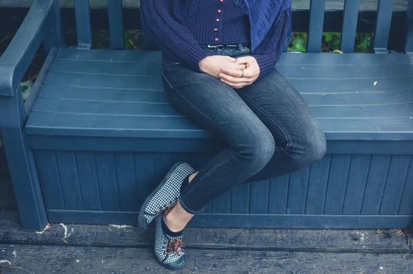 Young woman sitting on bench outside — Stock Photo, Image