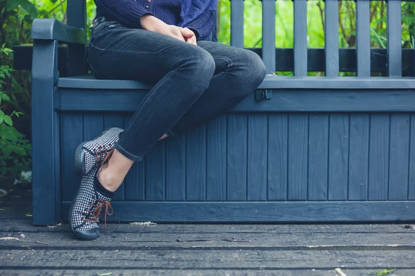 Ung kvinna sitter på bänken utanför — Stockfoto