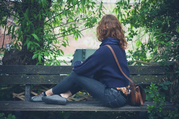 Žena sedí na lavičce v lese — Stock fotografie