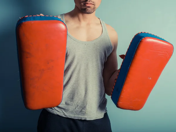 Dövüş sanatları yastıkları ile atletik genç adam — Stok fotoğraf