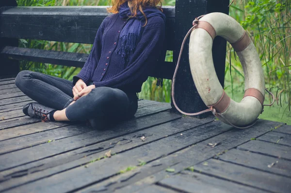 Mujer sentada en la cubierta junto al estanque en el bosque —  Fotos de Stock