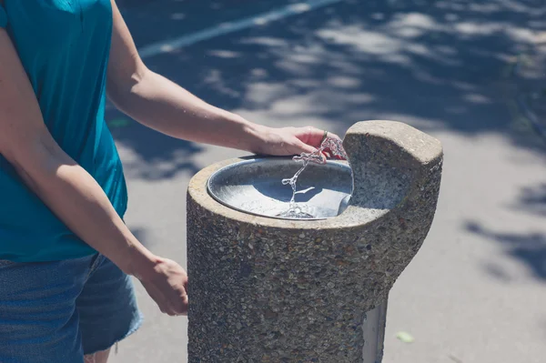 Young woman by water fountain — Stock Photo, Image