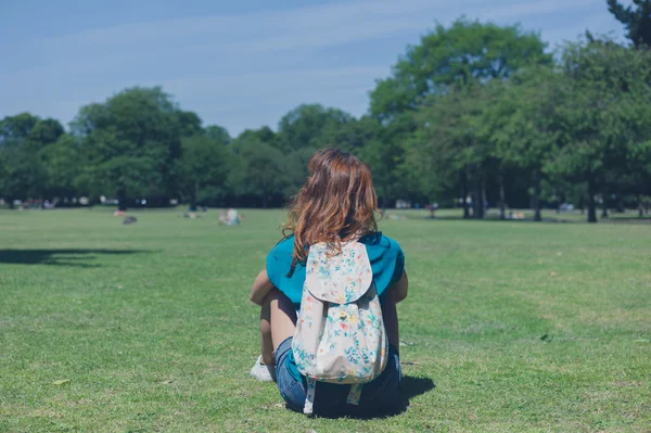 Молодая женщина с рюкзаком отдыхает в парке — стоковое фото