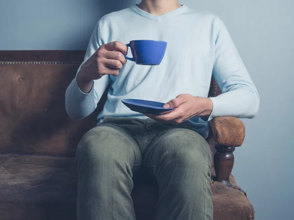 Άνθρωπος στον καναπέ, πίνοντας τον καφέ — Φωτογραφία Αρχείου