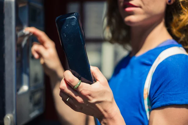 Молода жінка використовує громадський телефон — стокове фото