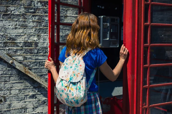 Молодая женщина входит в телефонную будку — стоковое фото