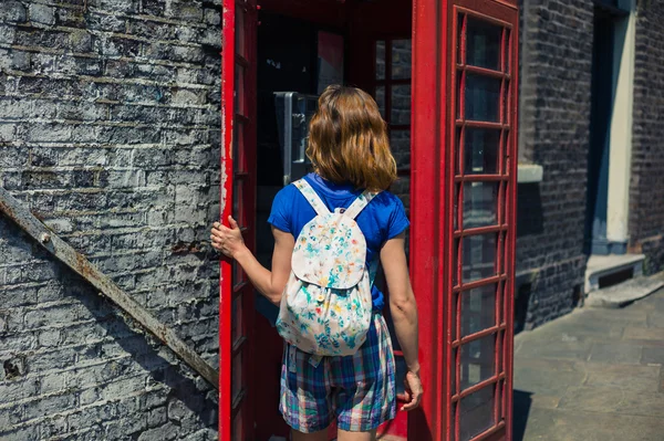 Genç kadın bir telefon kulübesine girerek — Stok fotoğraf