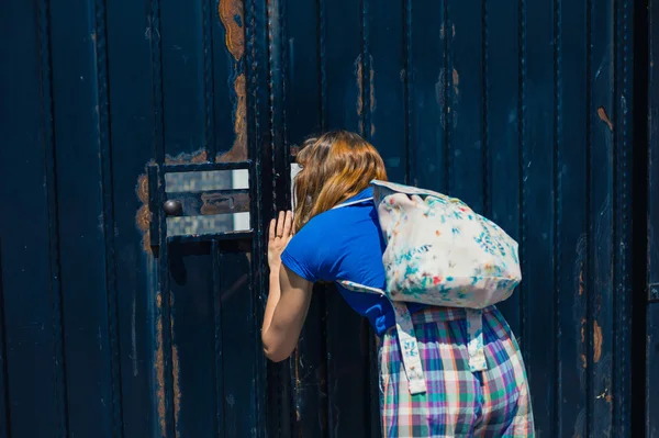 Jonge vrouw gluren door poort — Stockfoto
