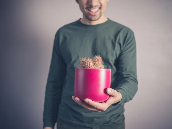 Ung man innehar en kaktus — Stockfoto