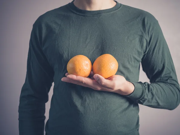 Young man holding two oranges — Stock Photo, Image