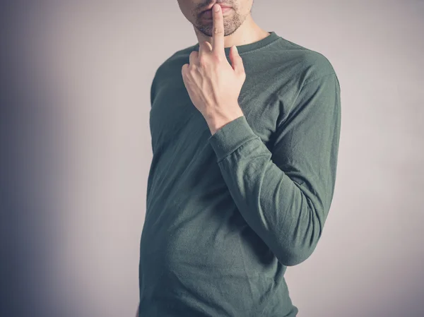 Berörda ung man med fingret på läppar — Stockfoto