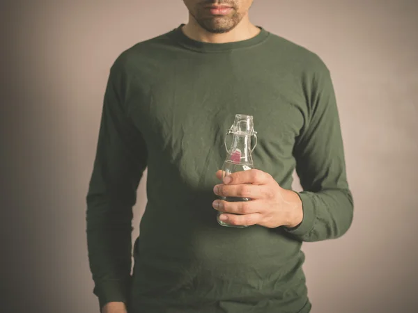 Joven sosteniendo una pequeña botella de vidrio — Foto de Stock