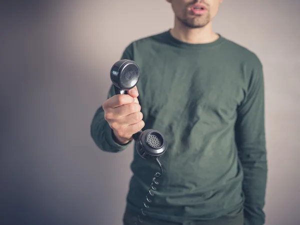 Jovem preocupado segurando telefone vintage Fotografia De Stock