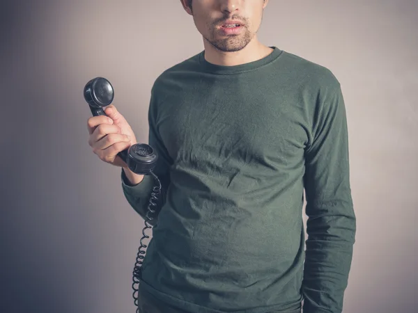 Ενδιαφερόμενο νέος άνθρωπος που κρατά vintage τηλέφωνο Εικόνα Αρχείου