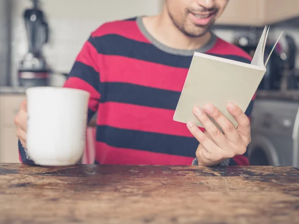Young man reading and drinking coffee — Stock Photo, Image