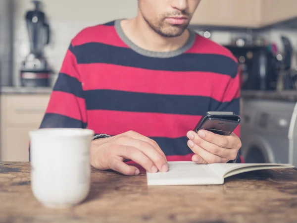 Junger Mann benutzt Smartphone und liest — Stockfoto