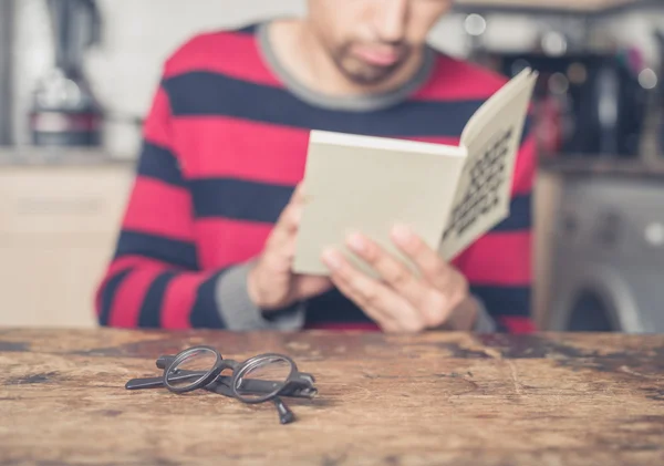 Uomo che legge libro in cucina — Foto Stock