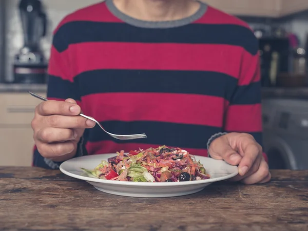 Joven comiendo ensalada en la cocina —  Fotos de Stock