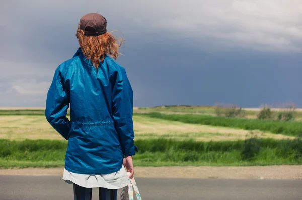 Jonge vrouw permanent door langs de weg in het land — Stockfoto