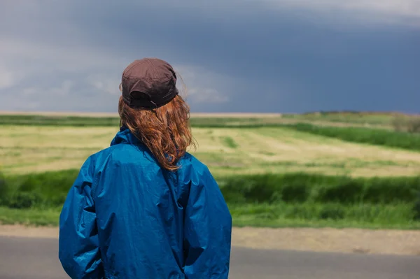 Jonge vrouw permanent door langs de weg in het land — Stockfoto