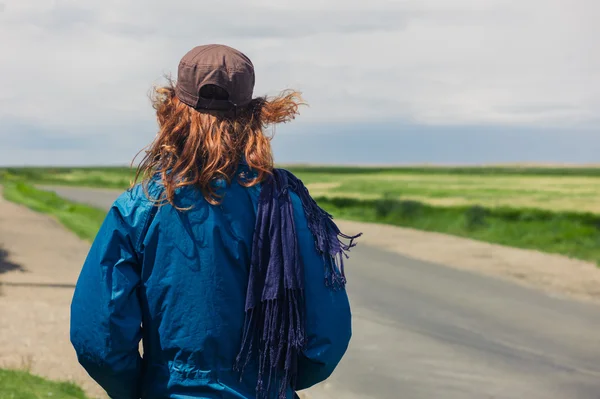Mujer joven parada al borde de la carretera en el país — Foto de Stock