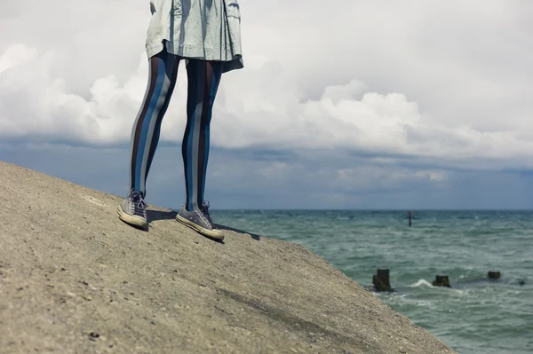 Legs of young woman standing by coast — Stock Photo, Image