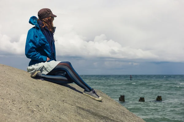 Mujer sentada en la defensa de las inundaciones junto al mar —  Fotos de Stock