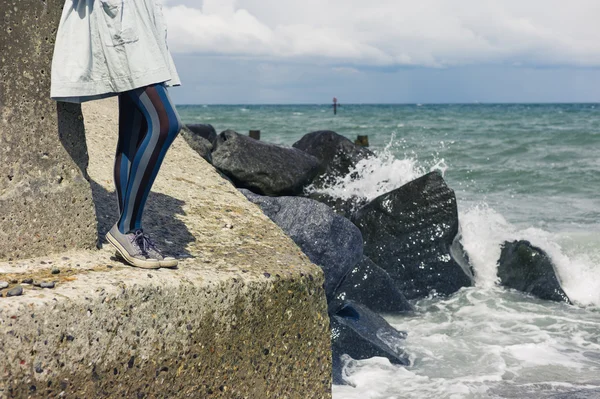 Pernas de mulher de vestido em pé na costa — Fotografia de Stock