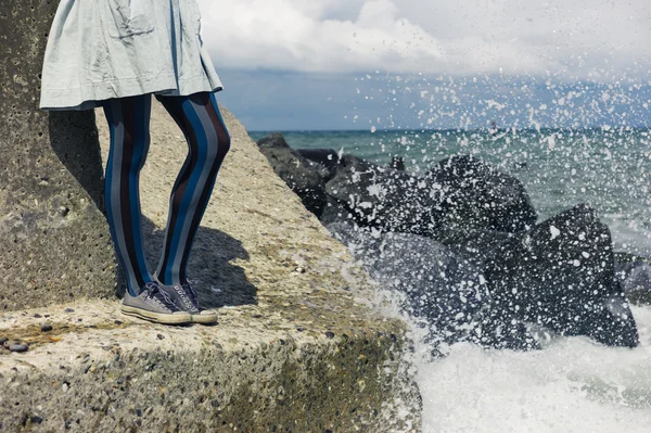 Legs of woman in dress standing on coast — Stock Photo, Image