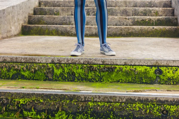 Naisen jalat seisomassa betonirakenteella meritse — kuvapankkivalokuva
