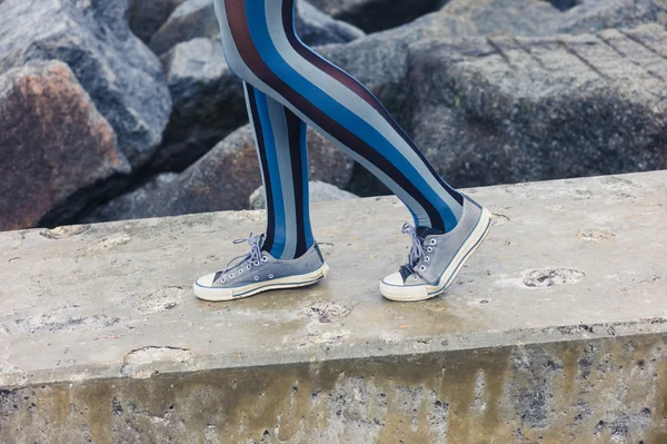 Jambes de femme debout sur une structure en béton par la mer — Photo