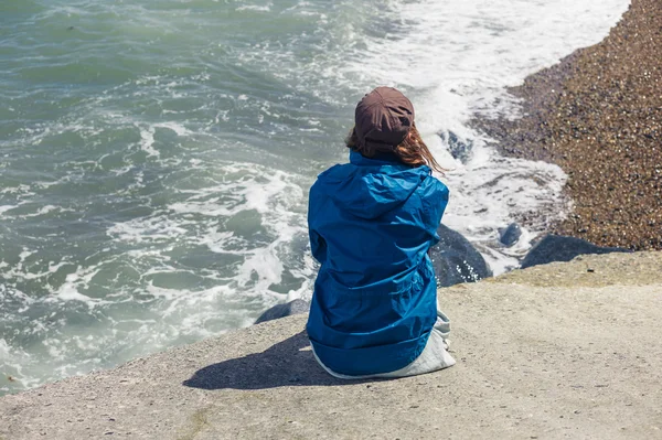 Woman sitting on flood defense by the sea — Stock Photo, Image