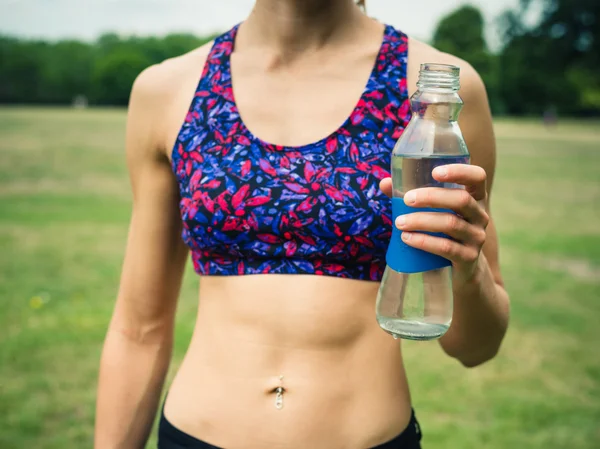 Fit vrouw met water fles in park — Stockfoto