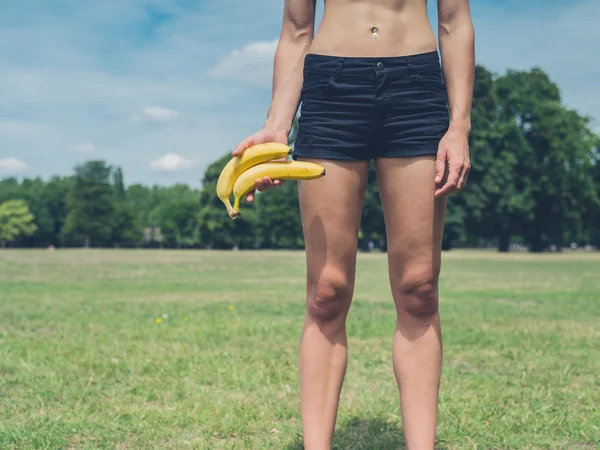 Mulher segurando duas bananas no parque — Fotografia de Stock