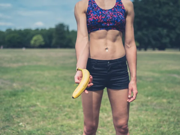 Fit woman offering banana — Stock Photo, Image