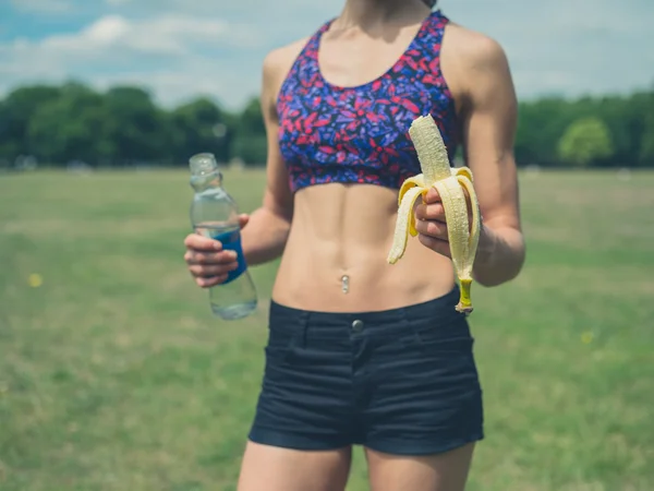 Vrouw in park met bananen en fles — Stockfoto