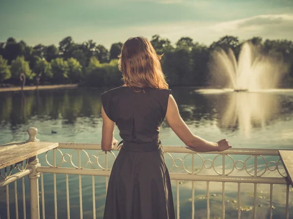 Jonge vrouw permanent door meer bij zonsondergang — Stockfoto