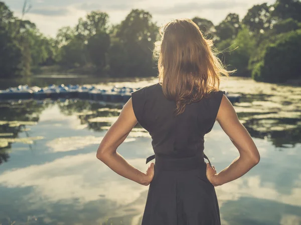 Молодая женщина, стоящая у озера на закате — стоковое фото