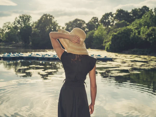 Elegant woman with hat by lake — Stock Photo, Image