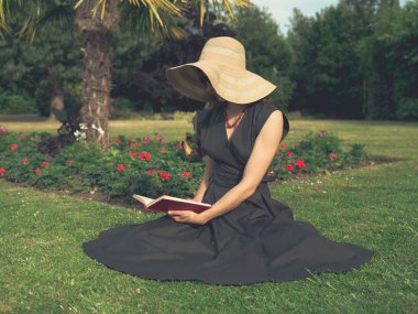 Zarif kadın parkta okuma şapka ile
