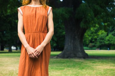 Park ağaç tarafından duran genç kadın