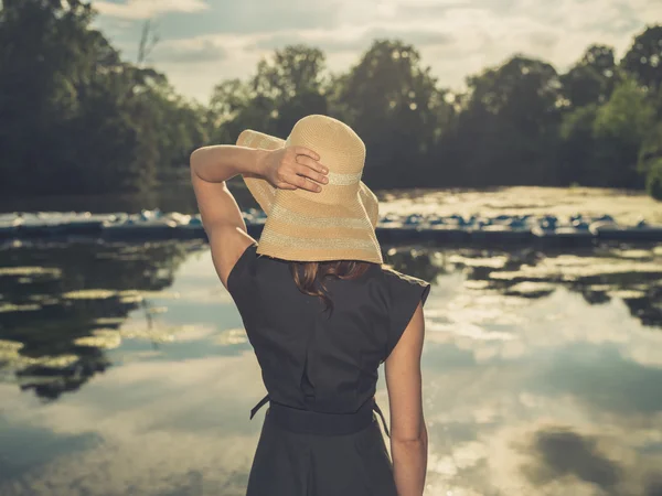 Elegant woman with hat by lake — Stock Photo, Image