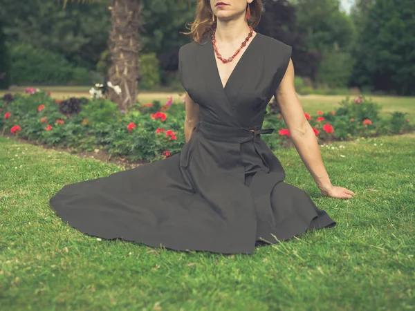 Elegant woman sitting on grass in park — Stock Photo, Image