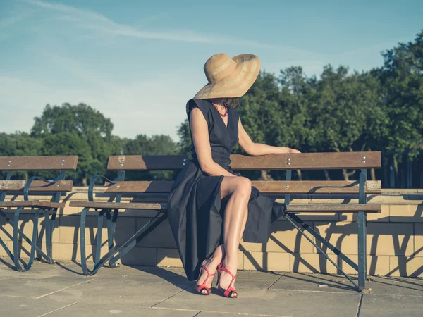 Elegant young woman sitting on park bench — Stock Photo, Image