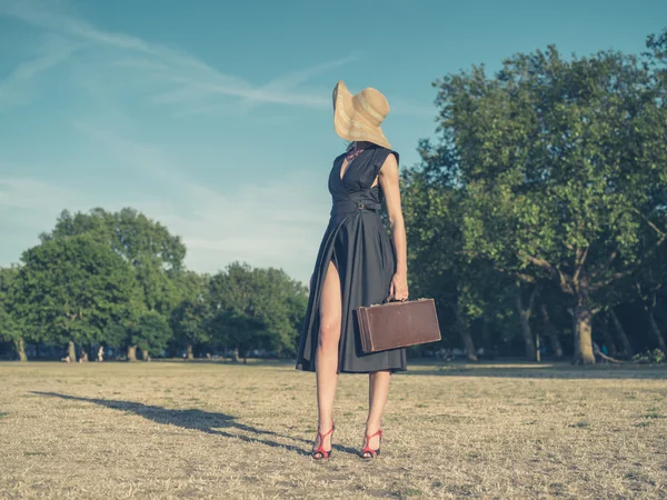 Elegante jonge vrouw met werkmap staan in park — Stockfoto